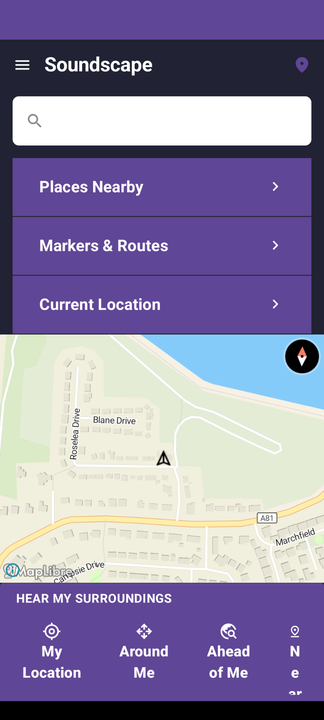 Screenshot of the Home screen. From top to bottom: a menu button and the Soundscape title, a search box, buttons for Places Nearby, Markers & Routes and Current Location, a map centred on the current location with a compass, and the Hear my surroundings buttons: My Location, Around Me, Ahead of Me and Nearby Markers.